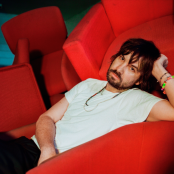 Artist Tame Impala on a red chair